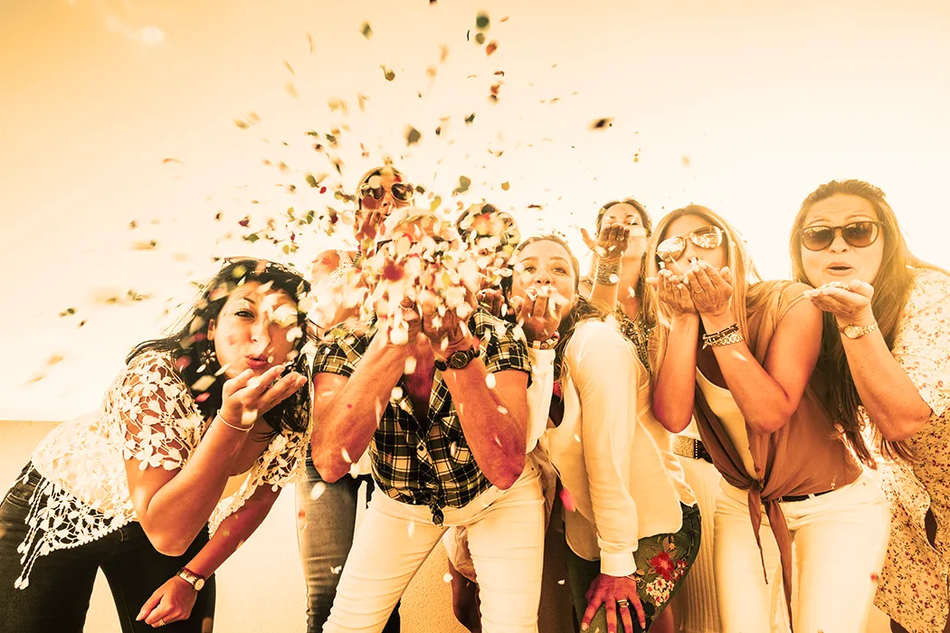 Group of people blowing confetti towards the camera